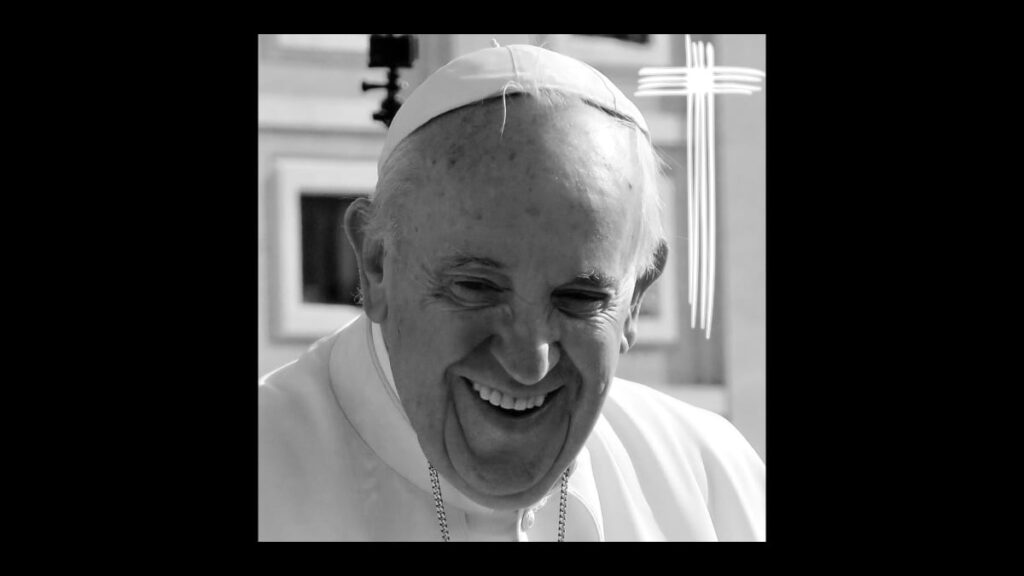 Das Schwarzweiß-Bild zeigt ein Portrait von Papst Franziskus, der in die Kamera lächelt. Oben rechts ist ein Kreuz zu sehen, das aus vier weißen Linien gebildet wird.