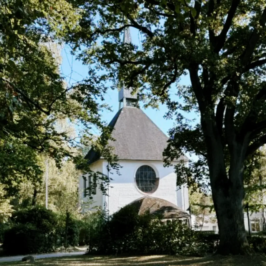 Das Bild zeigt die Kirche St. Michael in Bergedorf, umgeben von Bäumen und anderem Grün.