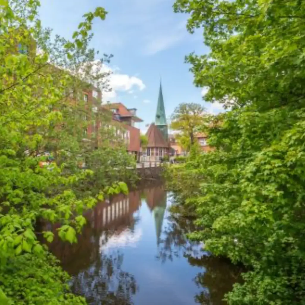 Das Bild zeigt die Kirche St. Petri und Pauli zwischen grün am wassergefüllten Schlossgraben gelegen.